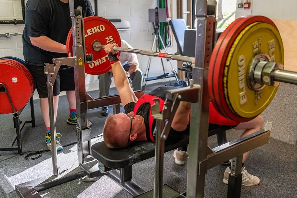 Andrew pressing 157.5 kg on the bench, with a spotter behind the bar