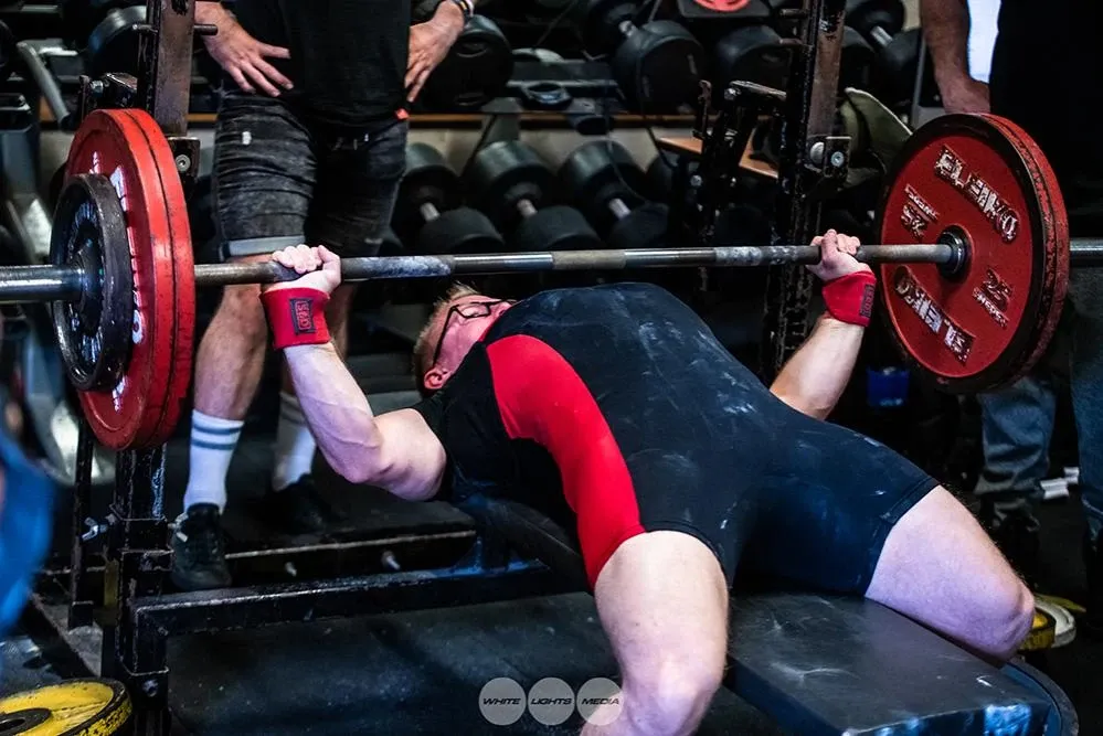 Andrew warming up with 140 kg on the bench press, with a spotter behind him