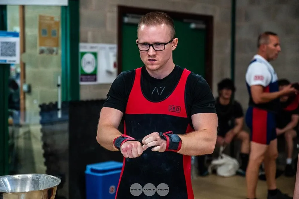 Andrew tightening his wrist wraps with a serious face, ready for the 170 kg attempt