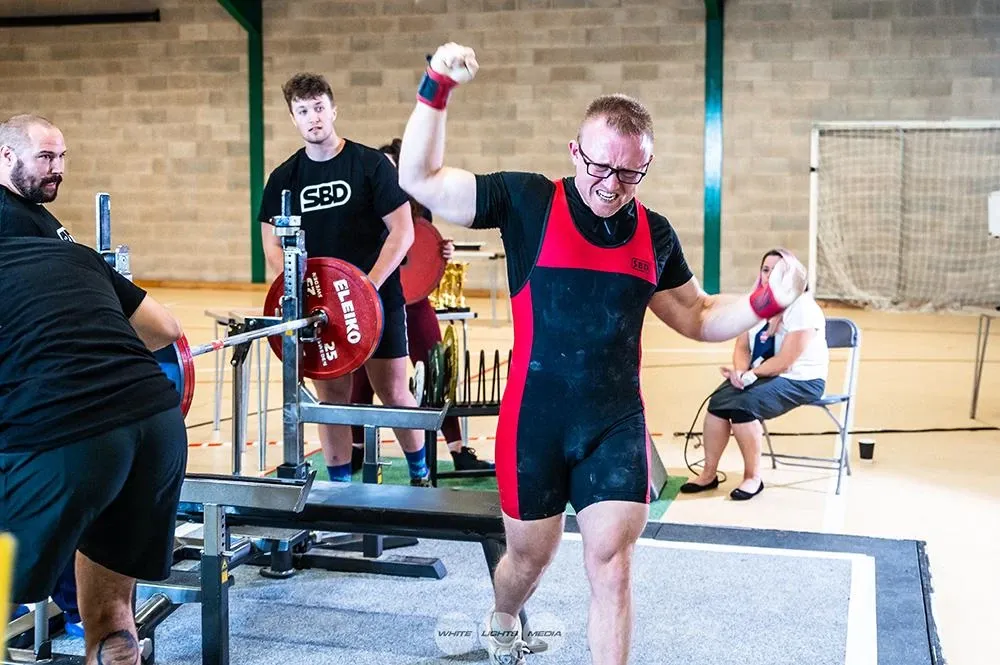 Andrew stepping off the bench with one fist raised after the good lift at 170 kg