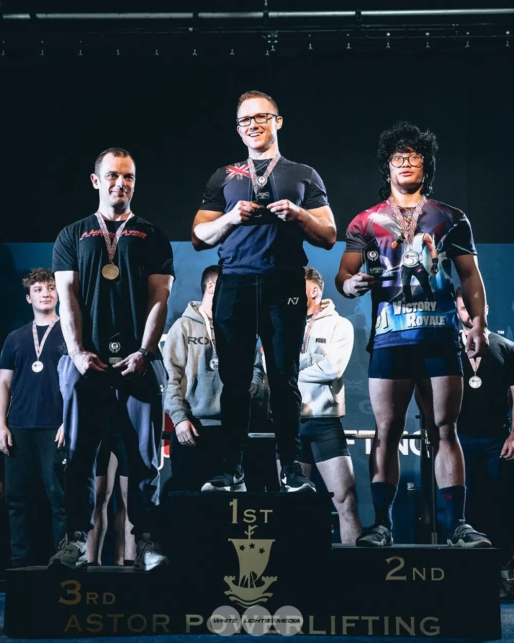 Andrew standing on the top step of the podium, with the second- and third-placed lifters either side
