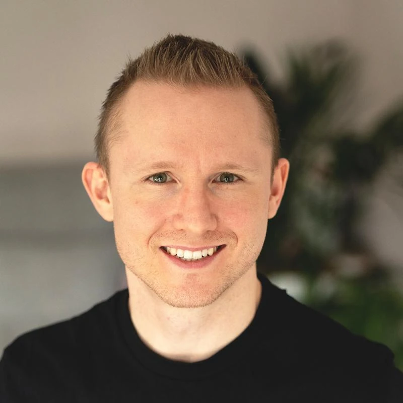 Head-and-shoulders portrait of Andrew smiling, in a black T-shirt