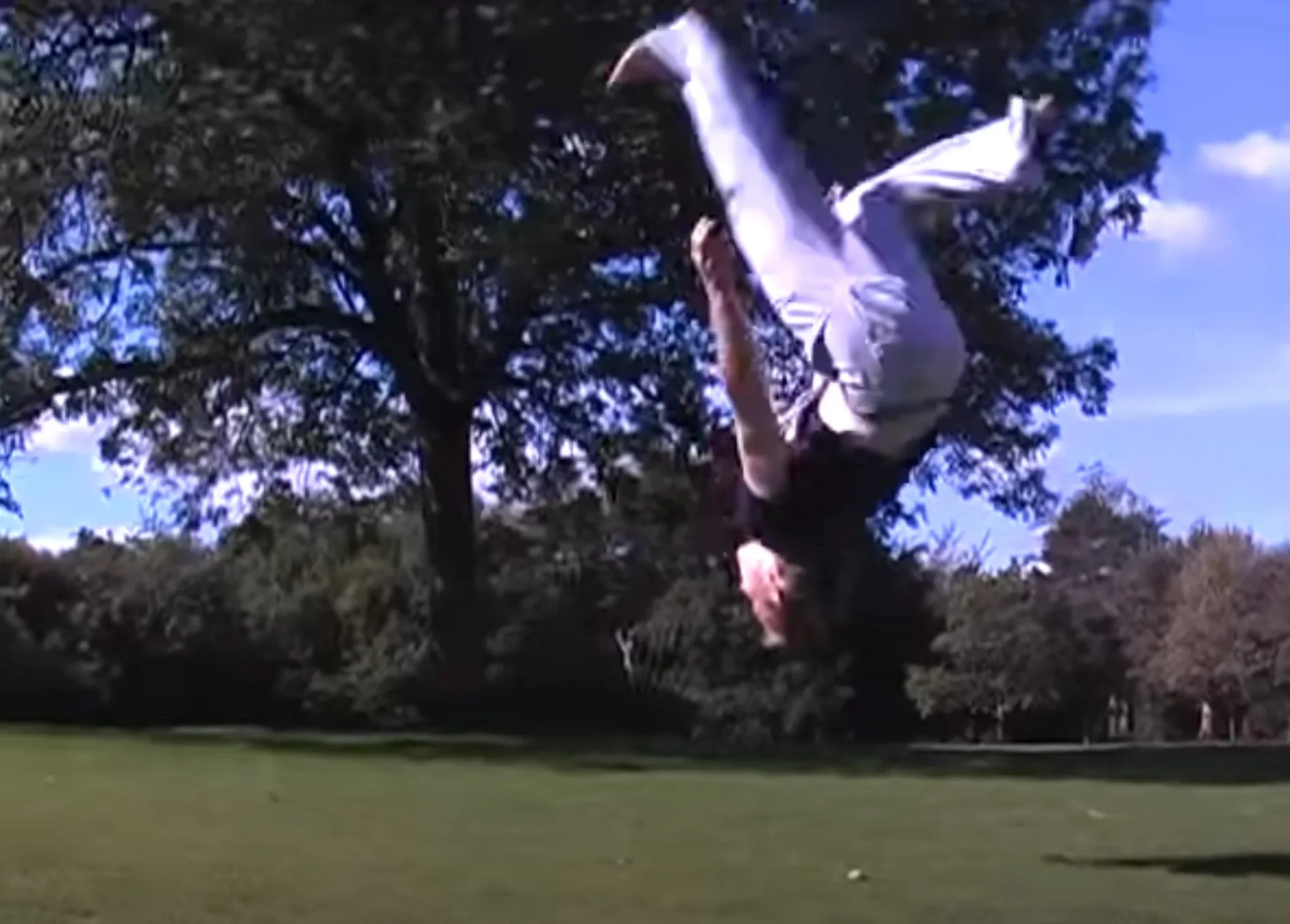 Andrew upside down in mid-air performing a backflip kick in a park