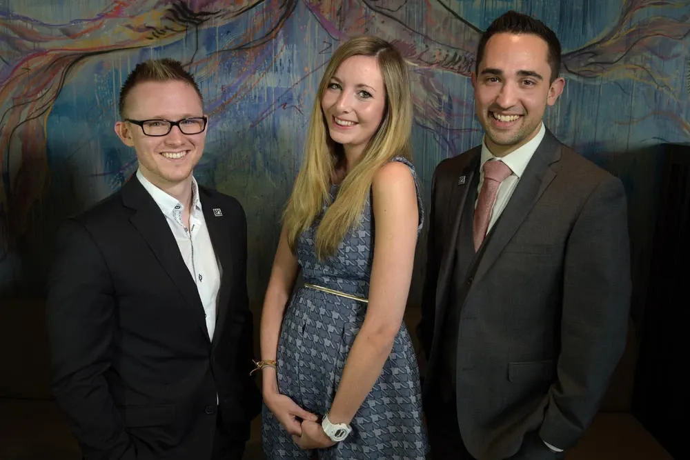 Andrew with fellow technology finalists Hannah Quinton and Mike Brooman, smiling in front of a painted mural
