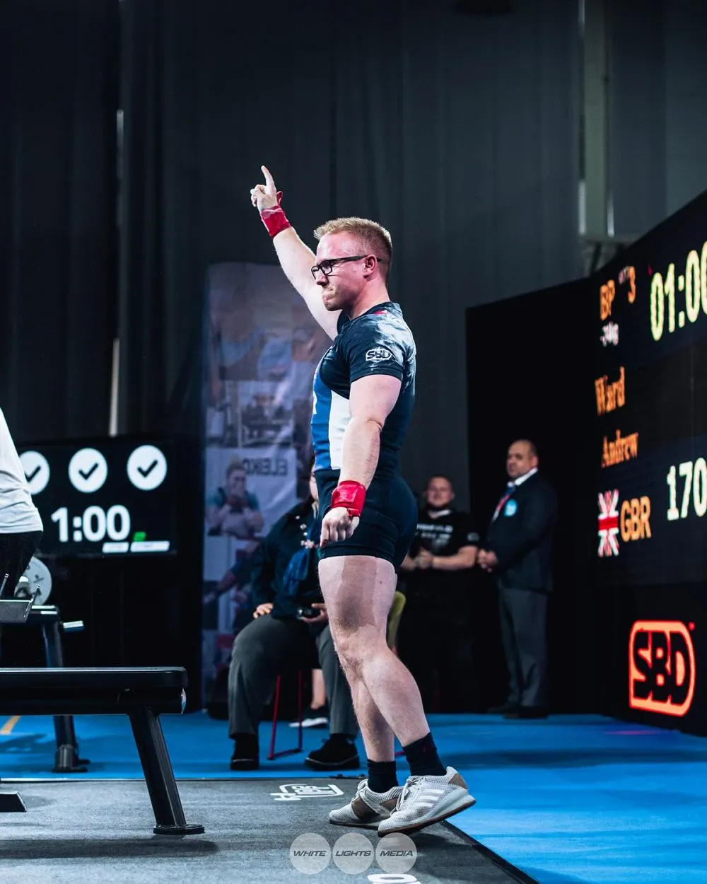 Andrew pointing to the sky after his 170 kg bench press, with the scoreboard showing three good lights and 170 beside his name