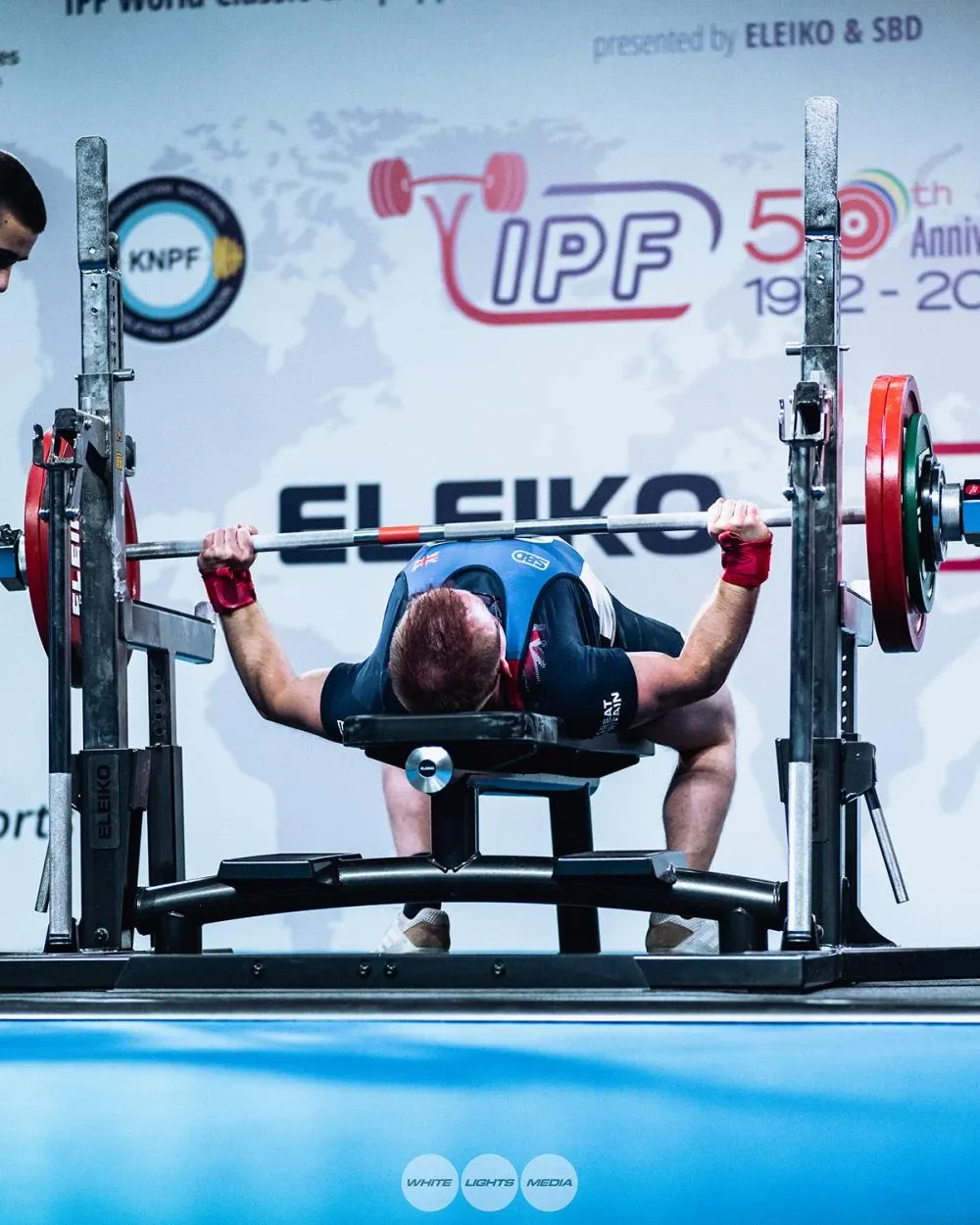 Andrew on the bench pressing his 152.5 kg opener, in front of the IPF and Eleiko backdrop