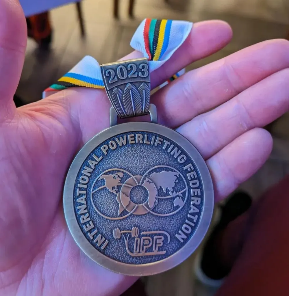 Close-up of the 2023 IPF bronze medal in Andrew’s hand