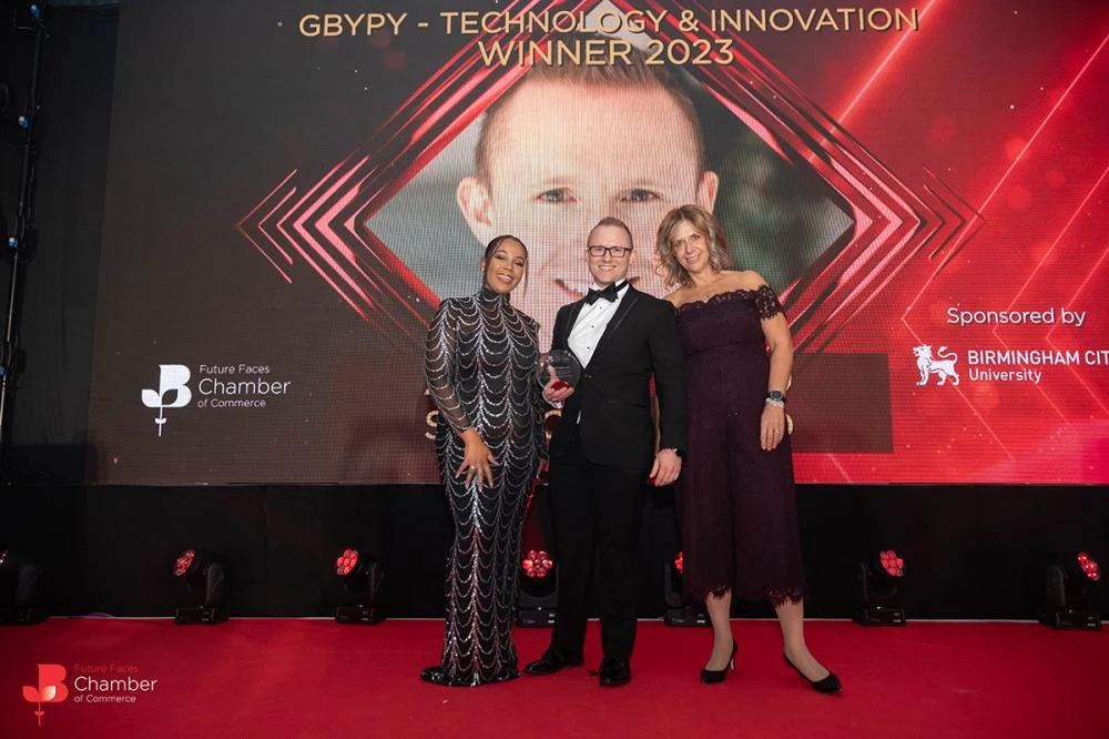 Andrew in black tie on stage with the Birmingham Young Professional of the Year award, 2023