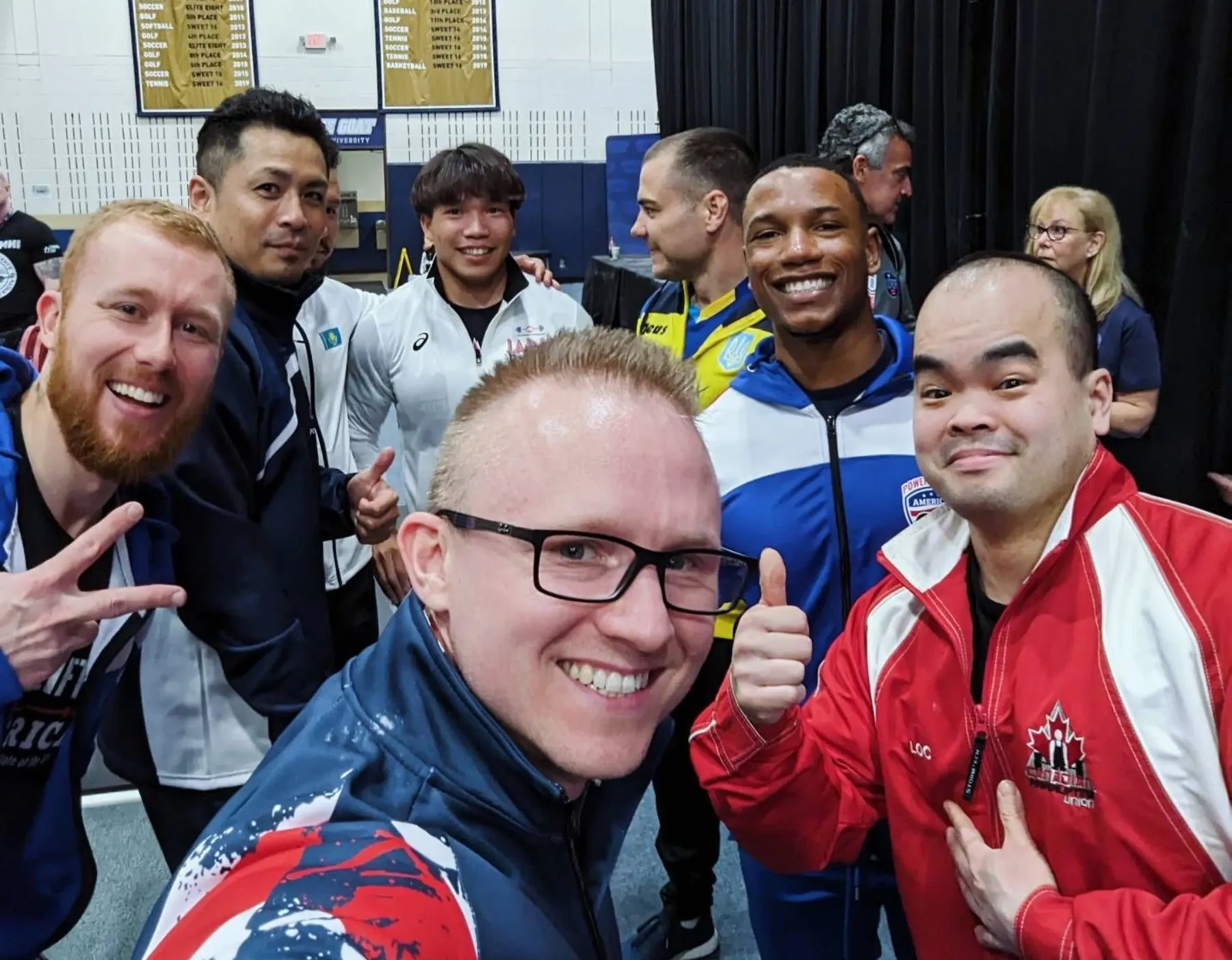 Selfie of Andrew, in a GB team jacket, with other lifters from the 74 kg class at the World Bench Press Championships in Austin, Texas