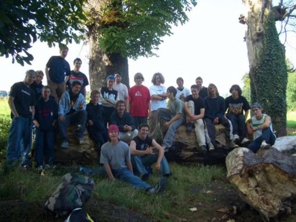 About 20 young people posing on and around a fallen tree trunk in a field at the first UK tricking gathering in 2005