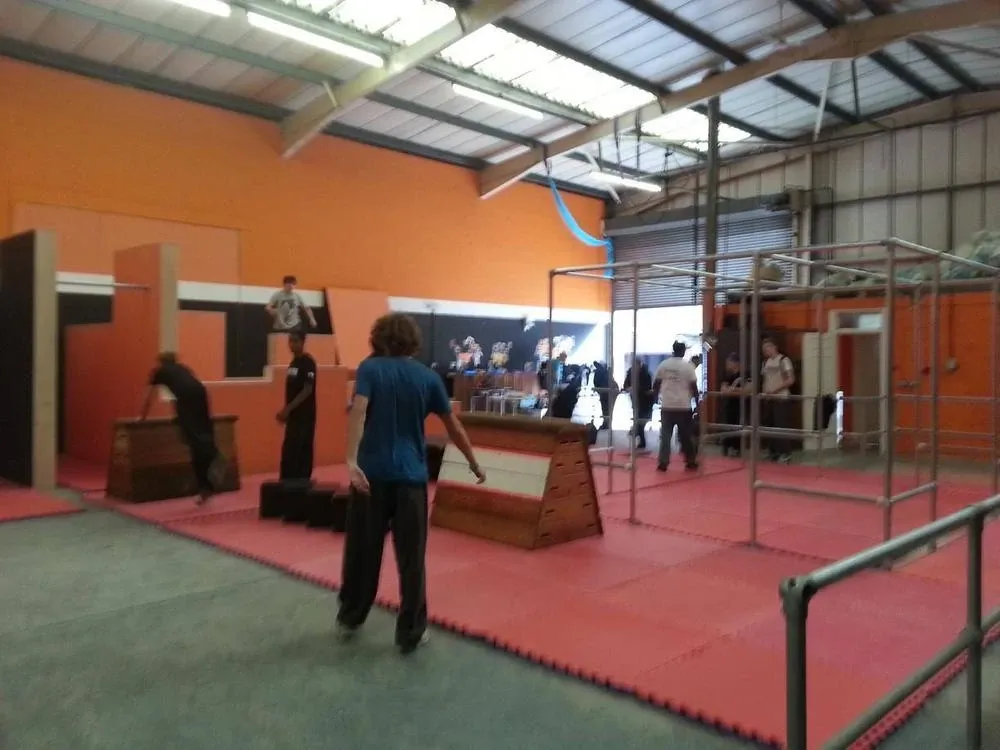 The early UTX training floor, with red mats, wooden vaulting boxes and scaffold bars in front of orange walls